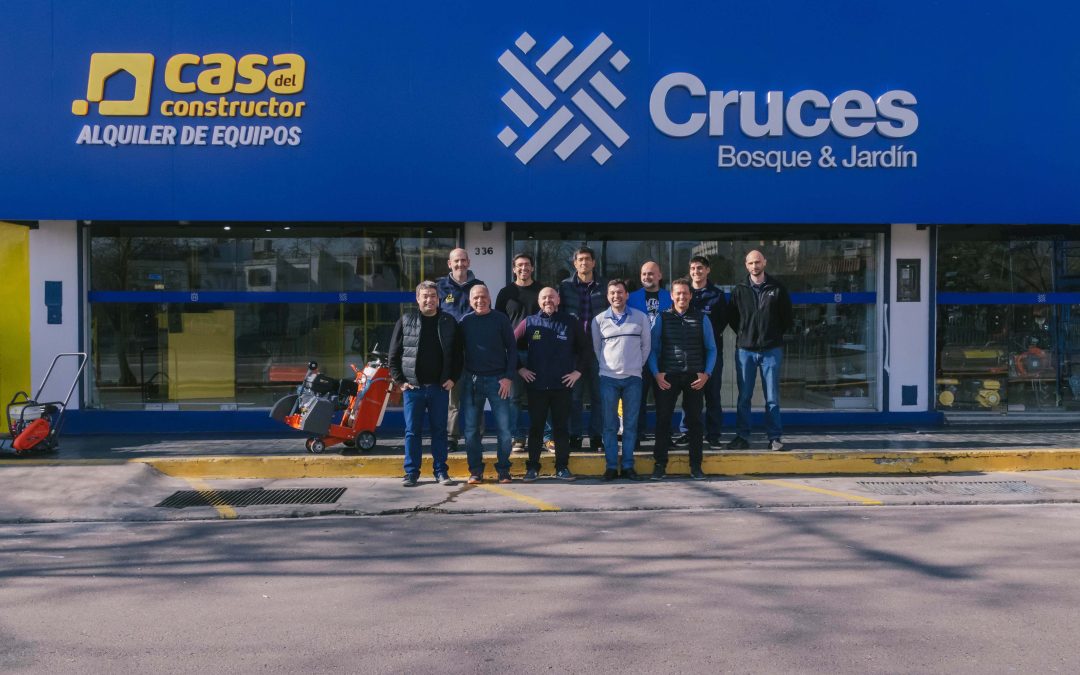 Group of people posing outside a blue storefront with construction equipment visible near the entrance.